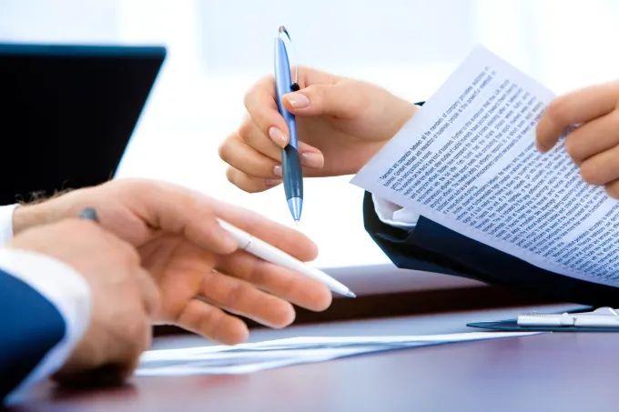 Affordable legal document help San Jose. People reviewing and preparing legal documents with pens in hand at an office desk.