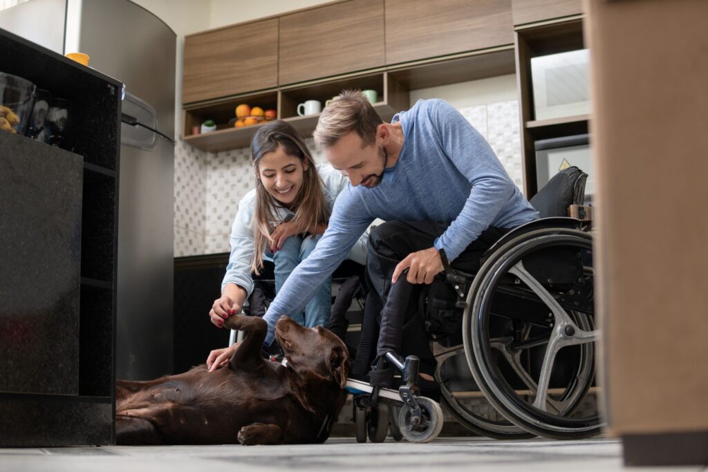 A man using a wheelchair and a woman joyfully petting their dog at home, symbolizing independence and Social Security Disability support.