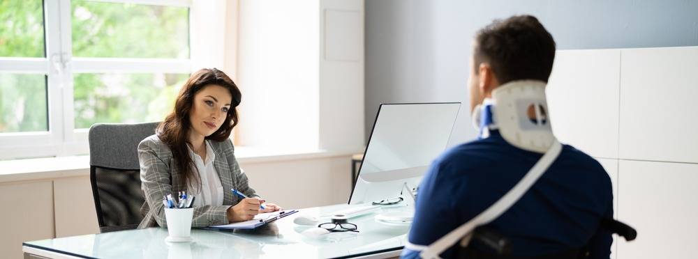 A professional woman consulting with a man wearing a neck brace, representing Social Security Disability support and local disability assistance services.