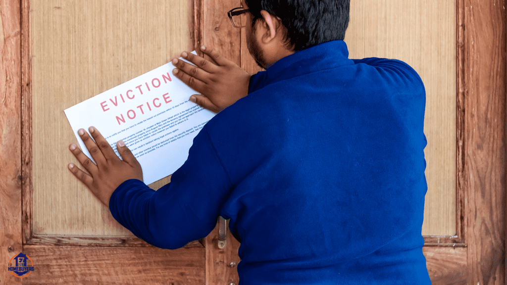A man in a blue jacket posting an eviction notice on a wooden door, symbolizing urgent eviction action and local unlawful detainer help services.