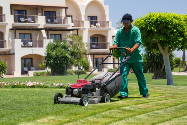 Professional landscaper mowing lawn in front of commercial property offering landscaping business services