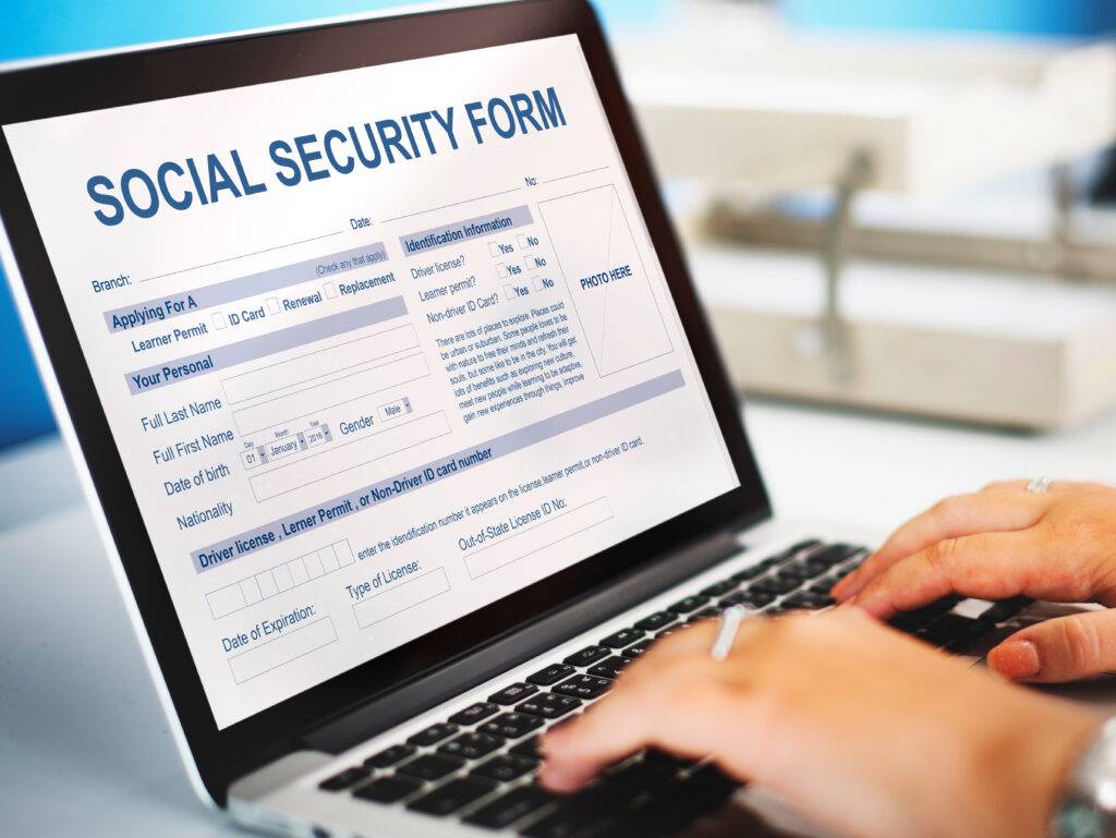 Person filling out a Social Security Disability application form on a laptop, representing SSDI and disability benefits assistance.