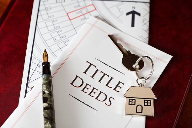 A title deed document with house keys and a pen, representing title transfer for a living trust.