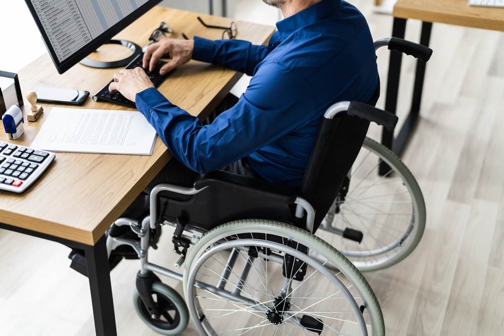 Man in wheelchair working at a computer desk—representing Social Security Disability assistance services by TrustPoint Disability & Legal Services in San Jose.