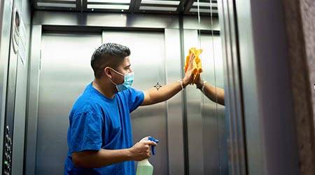 Janitor cleaning elevator interior as part of professional commercial cleaning services