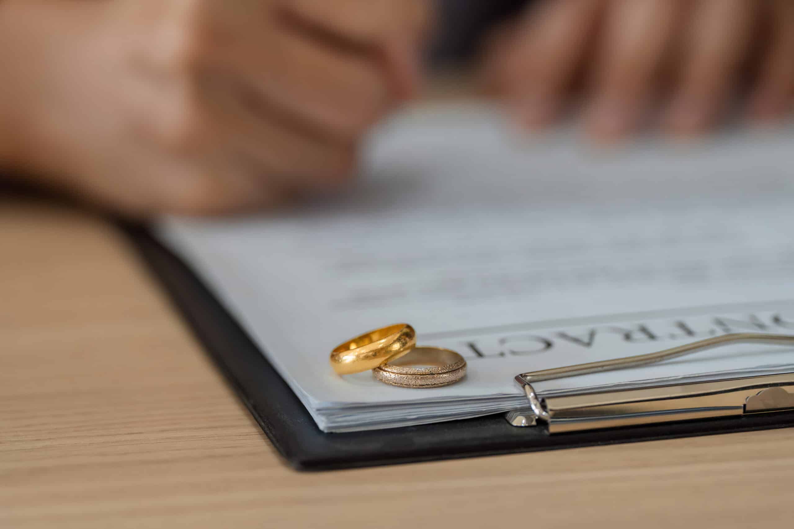 California divorce property settlement signing — wedding rings on marital agreement contract before recording the divorce deed transfer