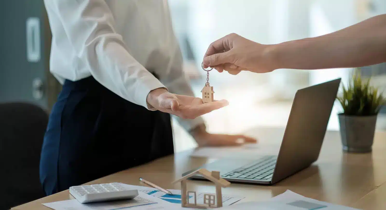 Interspousal transfer deed signing — California spouse handing house key over property transfer documents with California Prop 13 spousal exemption language